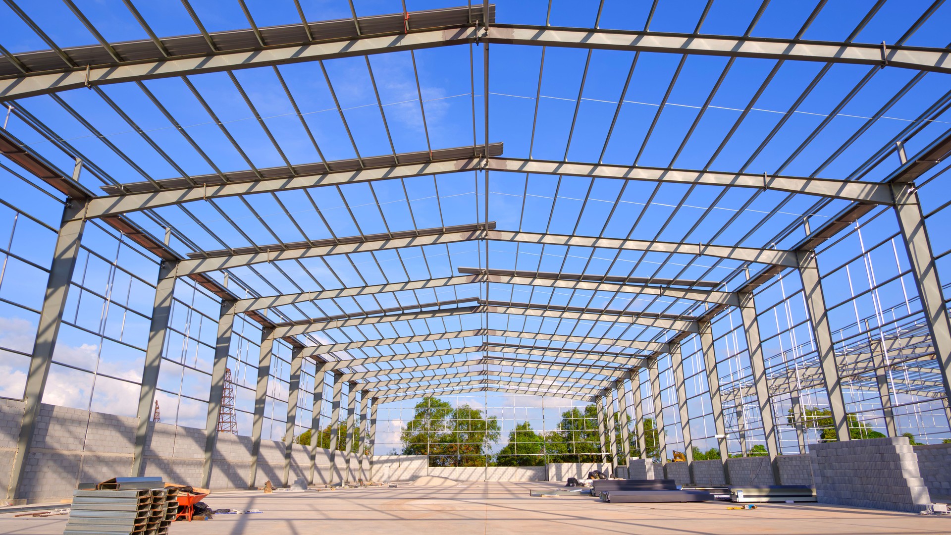 Metal structure of warehouse industrial factory building in construction site against blue sky background